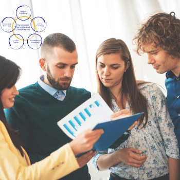 Four people standing together in an office environment and looking at a clipboard holding a document with a graph.