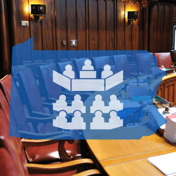 A transparent graphic of the state of Pennsylvania with a government icon is overlaid on an image of red leather chairs around a curved desk.